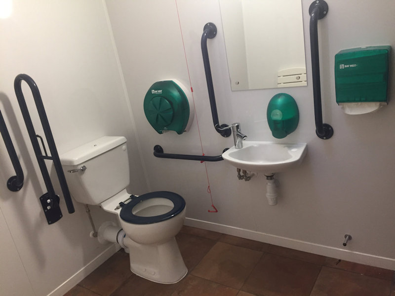 Wheel chair accessible wet room with shower, toilet and sink at Deepdale Camping